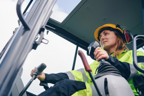 Two construction workers talking in front of heavy equipment.