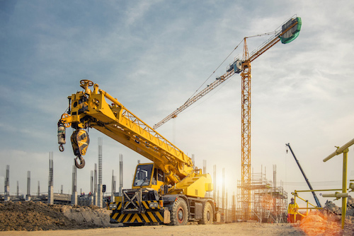 Two construction workers talking in front of heavy equipment.