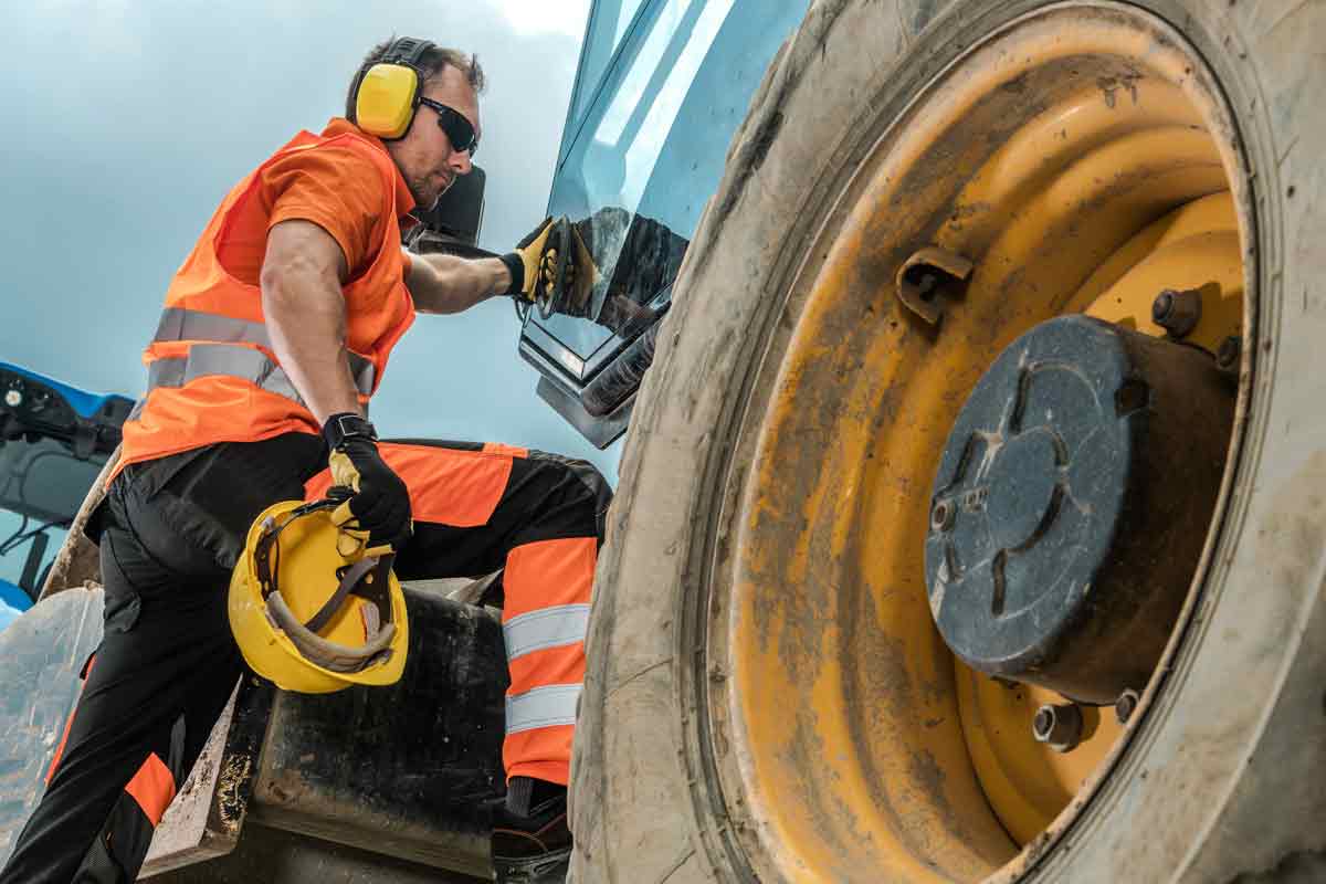 Two construction workers talking in front of heavy equipment.