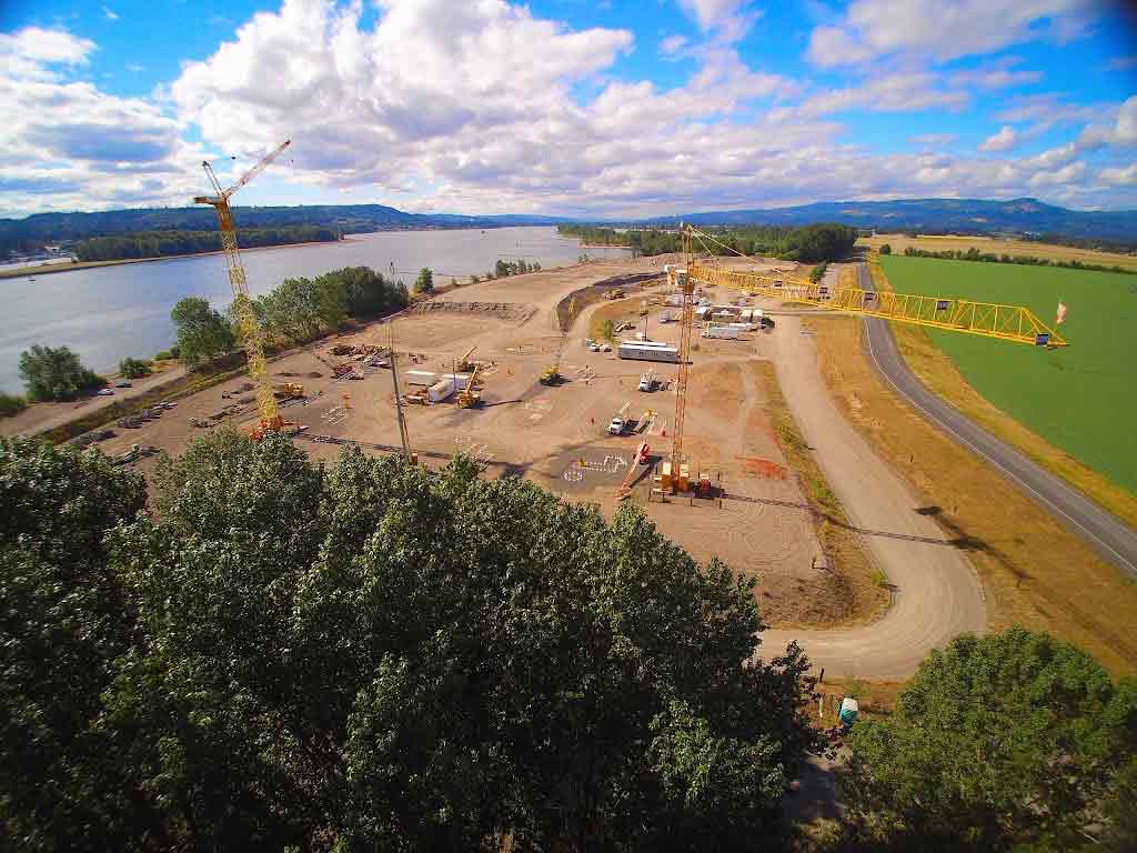 Two construction workers talking in front of heavy equipment.